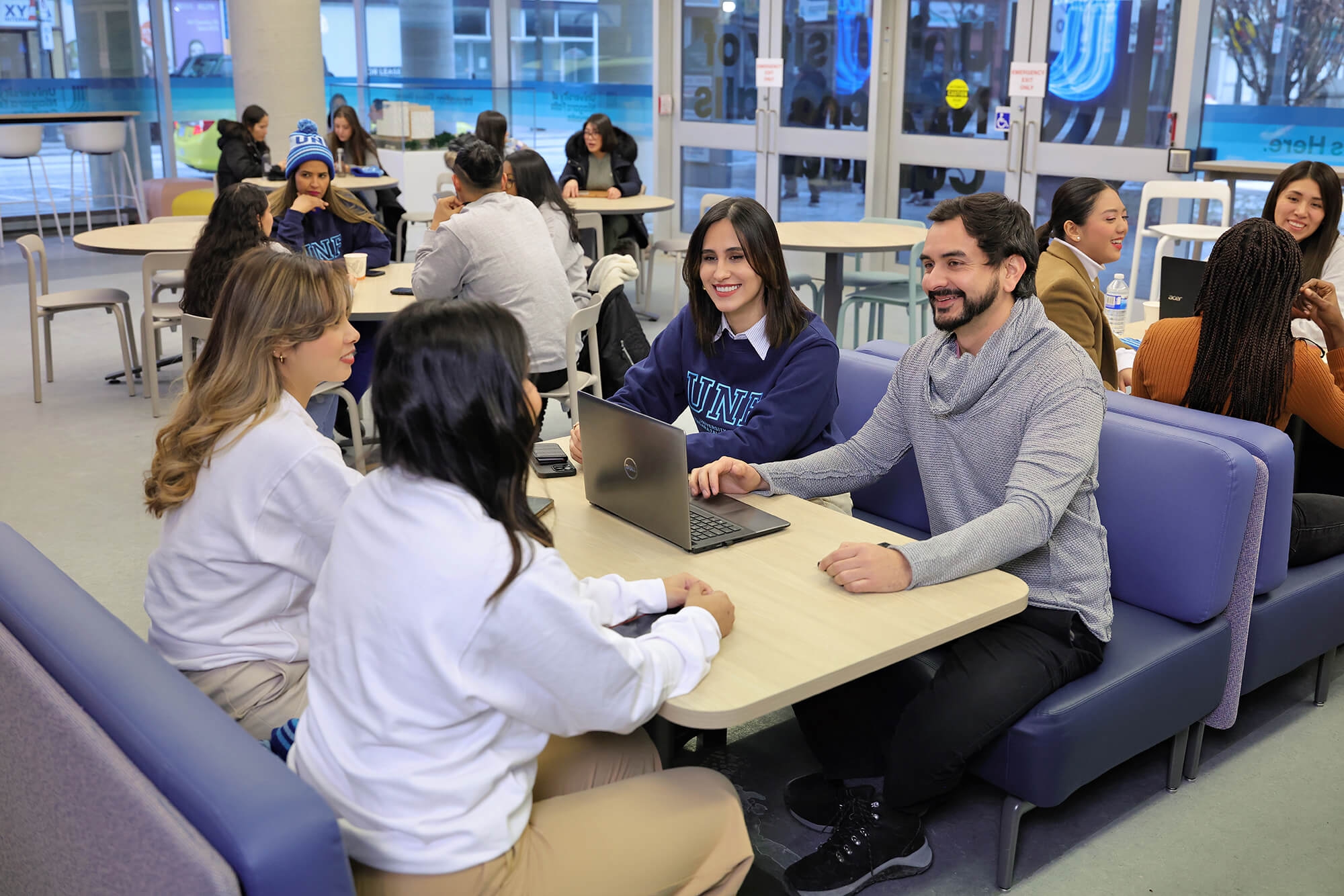 A diverse group of individuals with a laptop engaged in a discussion inside UNFC campus