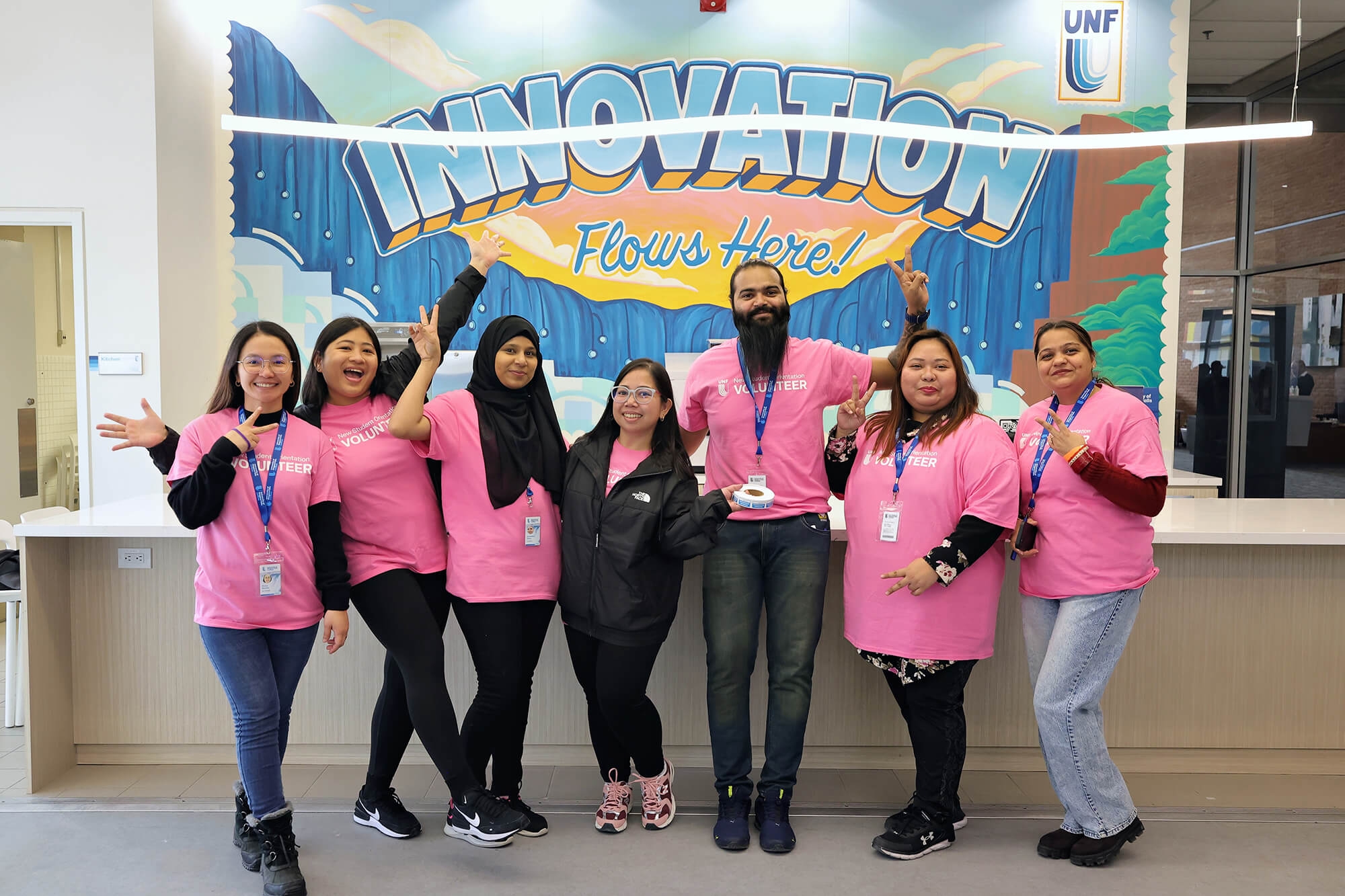 A group of diverse individuals wearing a pink Volunteer shirt posing for the camera