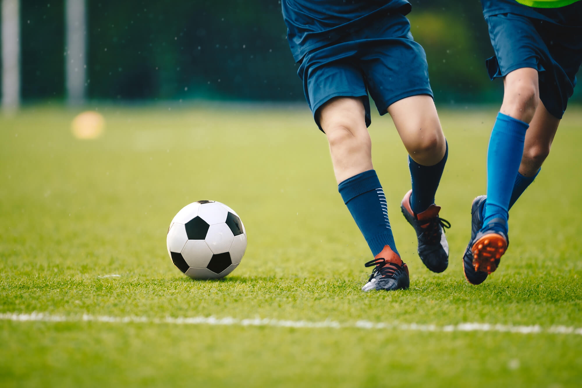 Two boys energetically kicking a soccer ball on a grassy field, showcasing their enthusiasm for the game