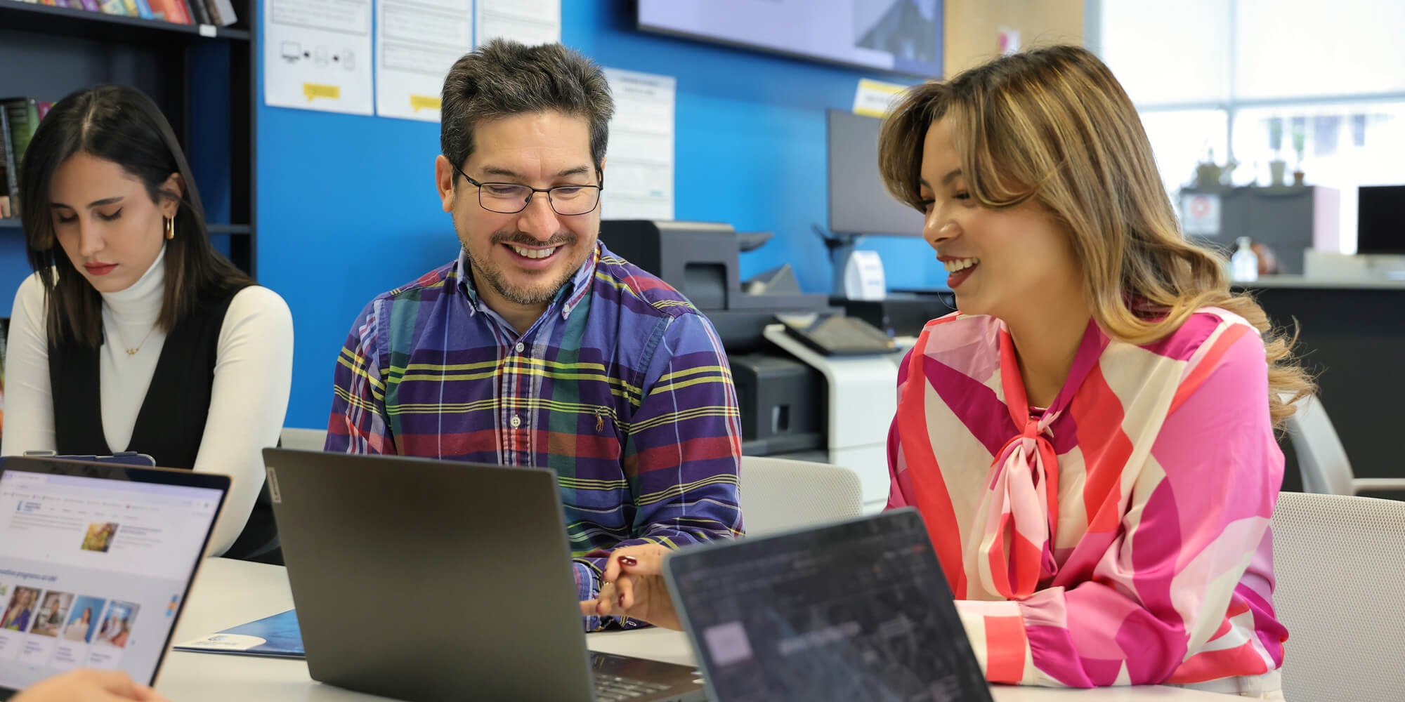 A man and a woman engaged in a cheerful discussion in front of a laptop