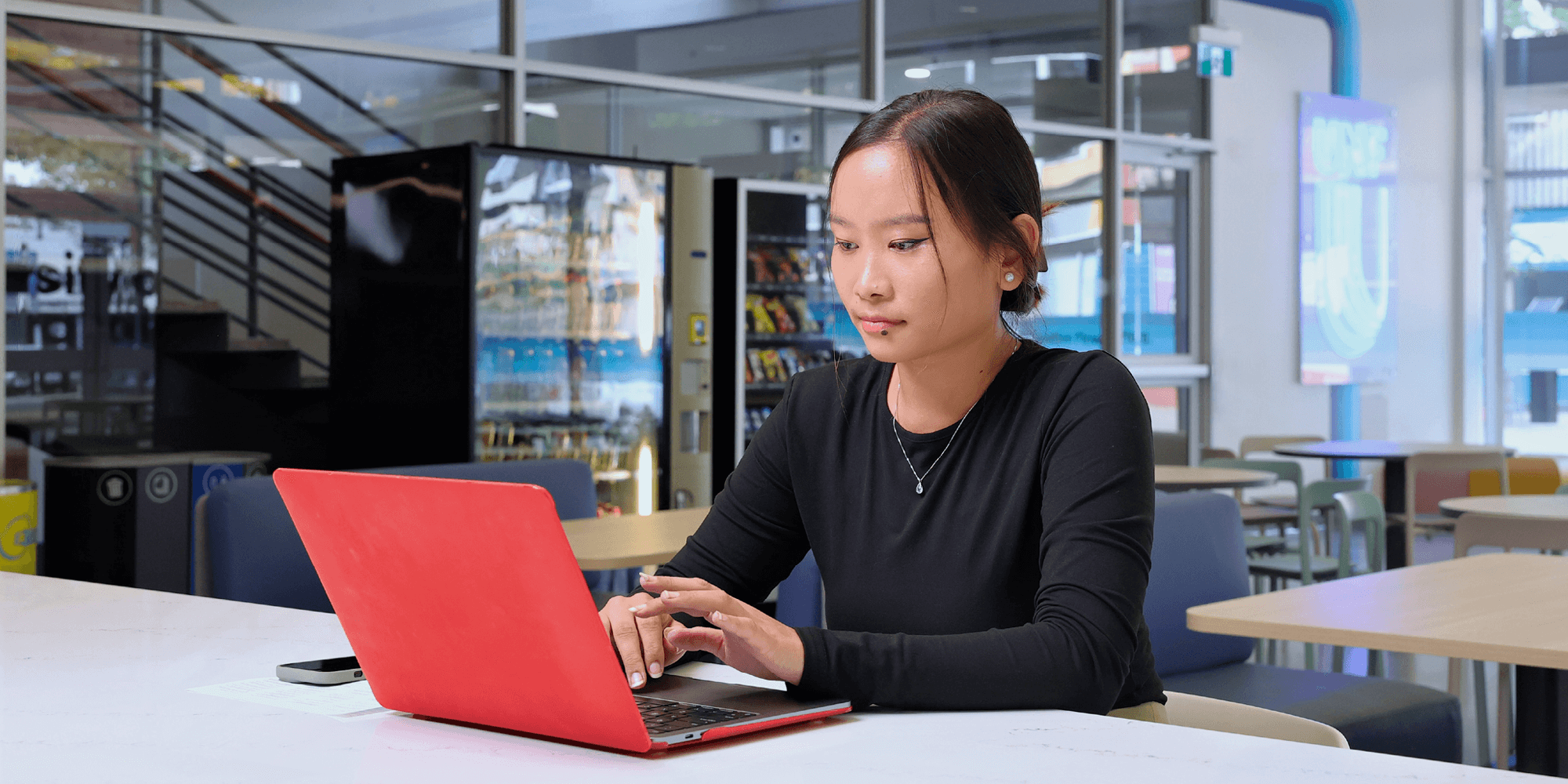 A female student with a laptop studying inside UNF cafeteria