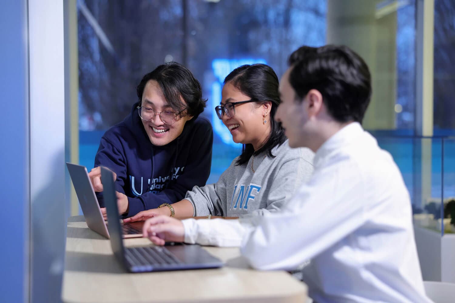 UNF students working on laptop and smiling