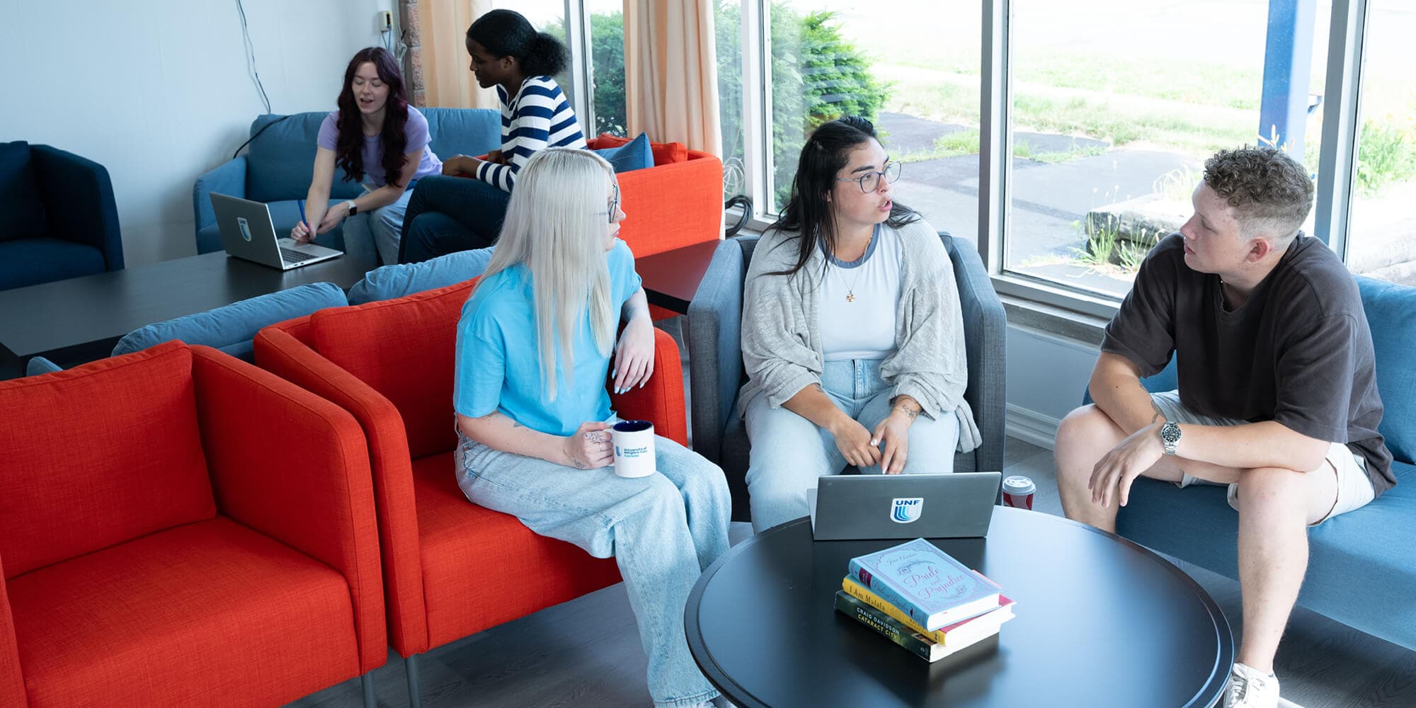 A diverse group of individuals sitting and talking with a laptop in front of them on a comfortable envinronment