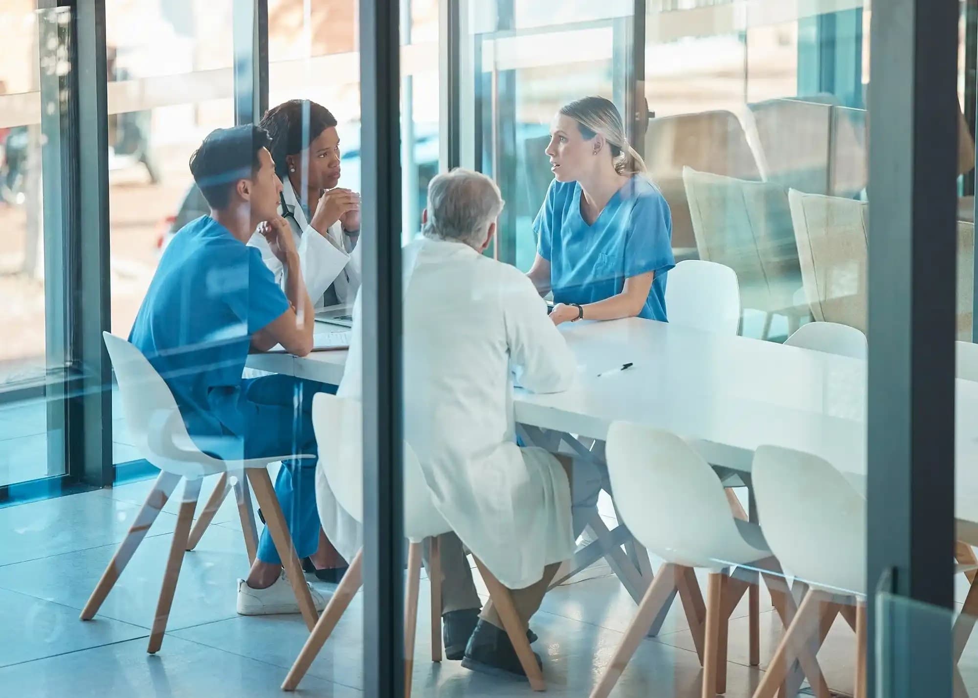 Group of medical professionals having a meeting inside a glassed wall room
