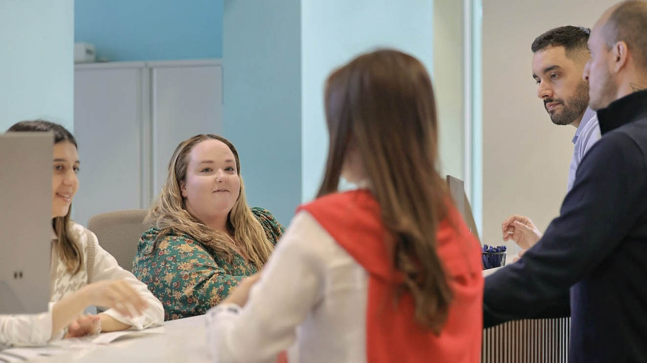 A group of people standing around a desk in a reception area