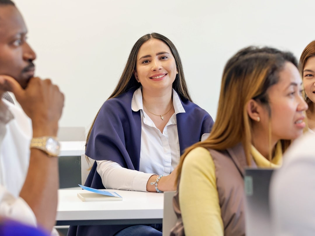 Photo of a university student smiling while seated on a classroom