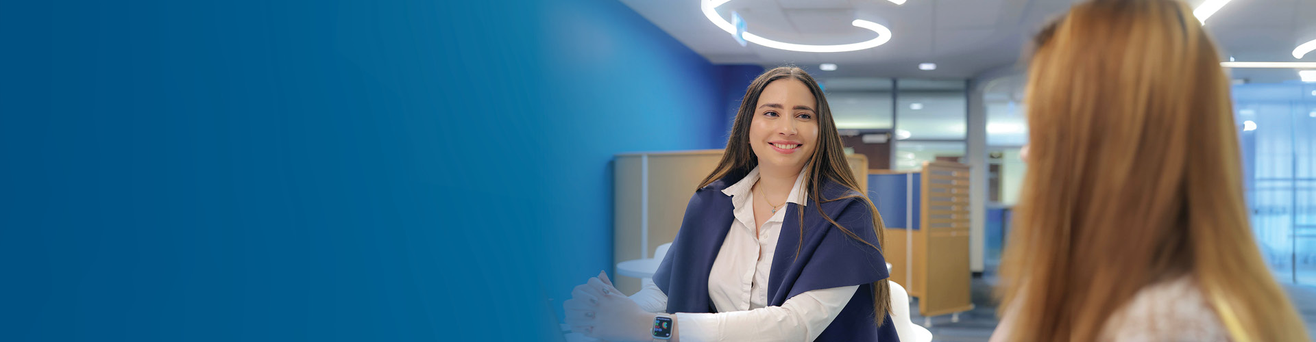 A woman with a cheerful expression while ga szing at a computer screen