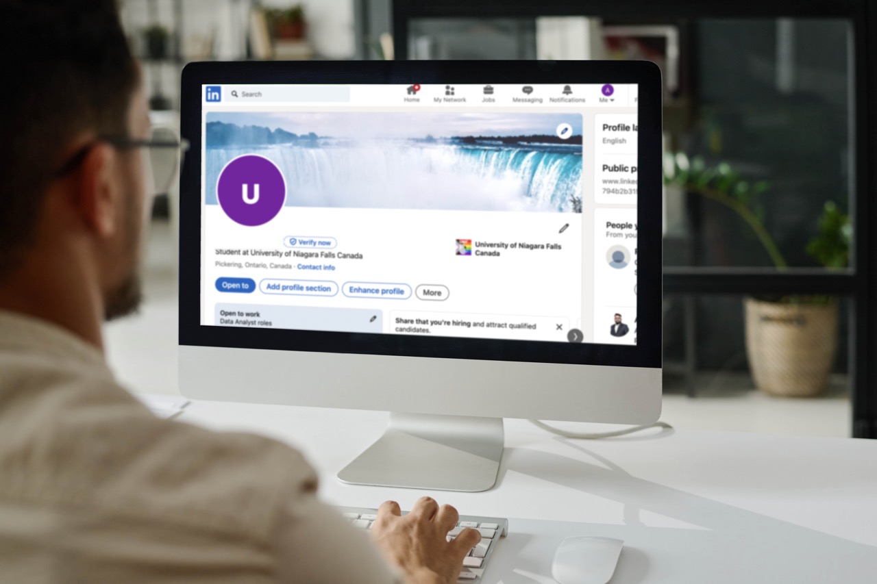 A man sitting at a desk, using Linkedin on his computer.