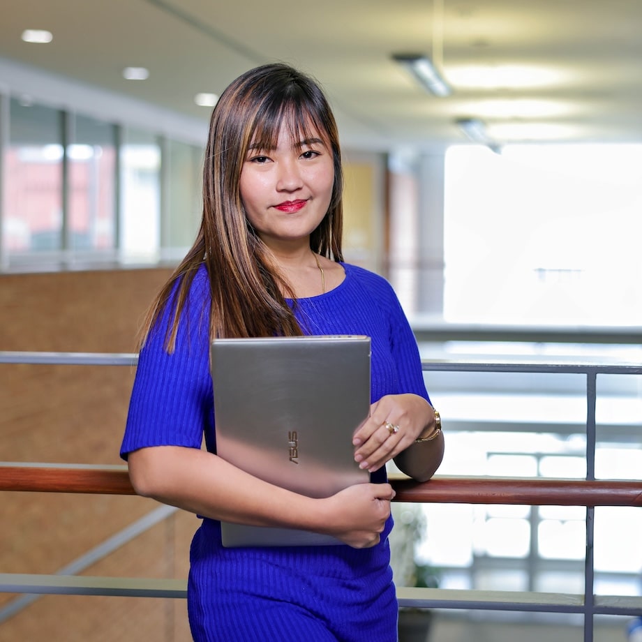 A woman dressed in blue holds a laptop