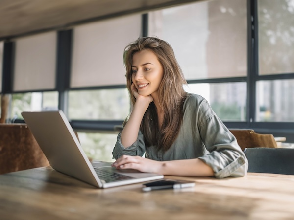 Young lady smiling in front of laptop while doing online education