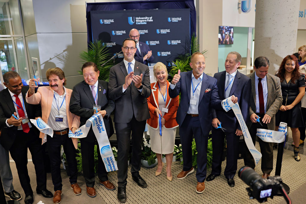 Several people gathered together, cutting a ribbon at a ceremonial event, marking the official opening of a new venture.