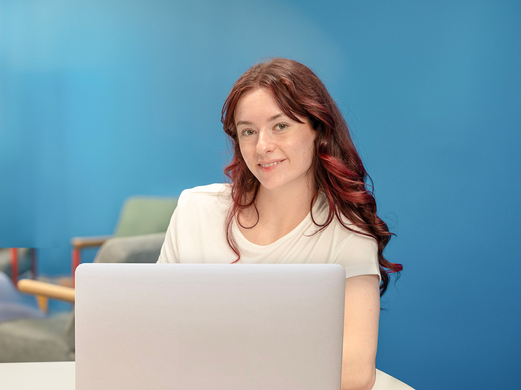 Young lady smiling in front of laptop while doing online education