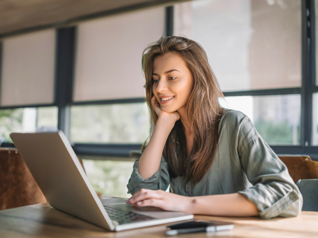 Young lady smiling in front of laptop while doing online education