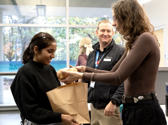 A woman is handing a bag to a girl in a well-lit room