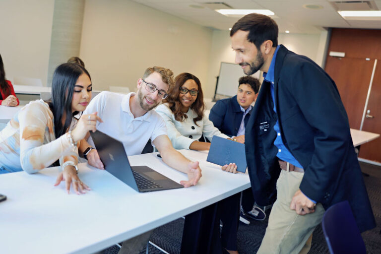 Students engaged in a classroom setting, focused on a laptop as they participate in a collaborative learning experience