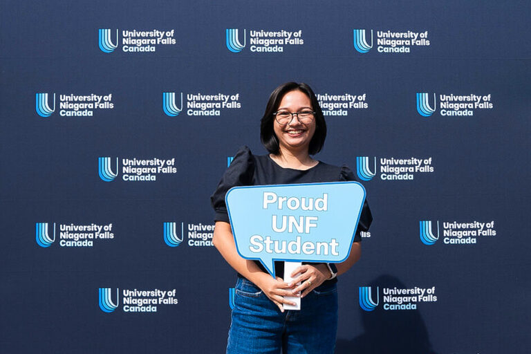 A UNFC student holding a photo prop that reads Proud UNF Student